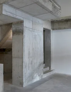 A concrete hallway with a staircase leading to a doorway, showcasing a utilitarian space with a commercial or industrial feel