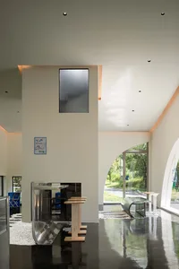 Open living area with white walls, chairs, a couch, dining table, refrigerator, and sink, well-lit and inviting