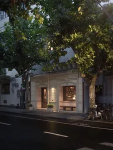 A modern building with a white facade, featuring a large window and two benches in front, with a bicycle parked nearby, set in a calm and inviting atmosphere