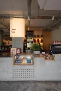 A cozy cafe interior with a wooden counter, potted plants, and various food and drink items on display