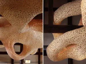 A modern abstract sculpture made of woven metal, resembling a fabric or spider web, adds character to a building's interior with an atmosphere of intrigue and creativity