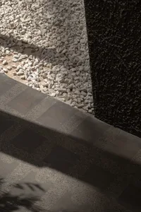 A hallway with a stone floor and scattered rocks, creating a natural and rustic ambiance with depth and contrast from the lighting
