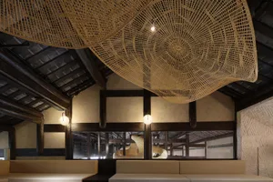 Cozy dining area with multiple chairs, benches, and woven wall hangings, set against a wooden ceiling