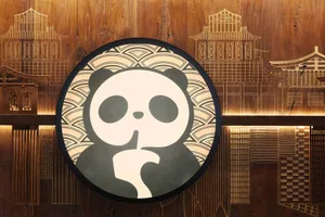 A stylized panda bear wearing a hat and holding its finger to its mouth in a playful pose
