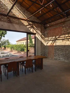 Dining area in a brick building with two wooden tables and modern chairs, exuding a rustic yet contemporary atmosphere
