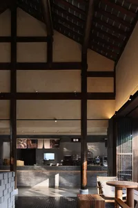 A spacious restaurant interior with stone walls, high ceilings, and multiple tables and chairs, lit by various lighting fixtures