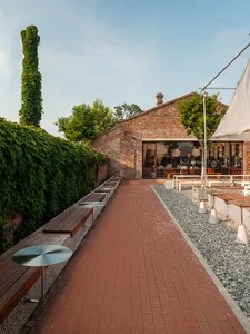 A brick walkway surrounded by dining tables, chairs, and benches in an inviting outdoor patio area