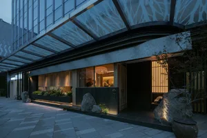 Elegant Asian restaurant with modern design, glass walls, and natural light, featuring tables and chairs in a welcoming atmosphere