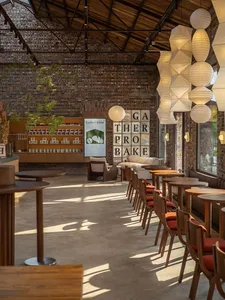 Cozy restaurant interior with a brick wall, wooden tables, and chairs, featuring multiple dining tables and a warm atmosphere