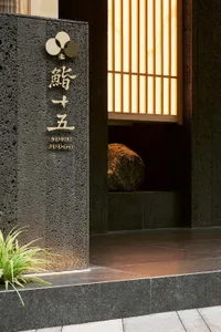 A stone entrance wall with Chinese characters, two large rocks, and a doorway create a traditional and cultural atmosphere