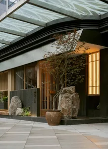 A serene Asian-style courtyard with a rock garden, potted plants, and a peaceful atmosphere