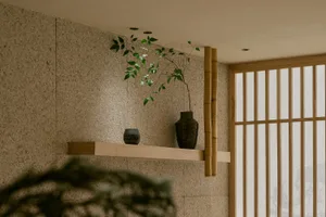 Cozy interior space with a wooden shelf displaying decorative vases and a potted plant, creating a warm and inviting atmosphere