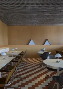 Cozy restaurant with wooden floors and walls, featuring tables and chairs in a warm and inviting atmosphere