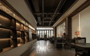 A well-lit lobby with a wooden floor, several chairs, and potted plants, designed for socializing or gatherings