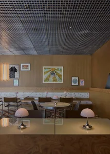 A restaurant dining area with multiple tables and chairs, potted plants, and clocks on the walls, creating a warm and inviting atmosphere