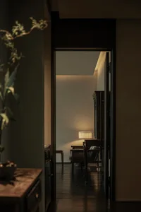 A cozy living space with a seating area, a couch, two chairs, a TV, and a potted plant, creating a warm and inviting atmosphere