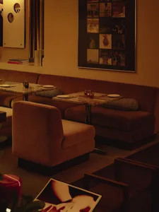 Cozy living space with brown couches and chairs arranged around dining tables, featuring cups and an inviting atmosphere