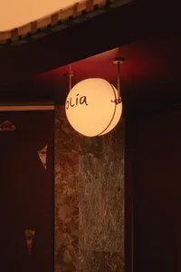 A warm and inviting living space with a round light fixture, clock, and two people, illuminated by the fixture's glow