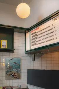A welcoming restaurant interior with a menu board above a counter, surrounded by books and a warm atmosphere