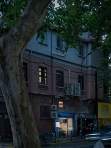 夜晚繁忙的城市街道，紅磚建築、交通號誌，以及遠處行行走的人