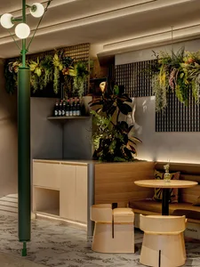A warm and inviting cafe with a dining table, wooden elements, and multiple potted plants, creating a cozy seating area with a lively atmosphere