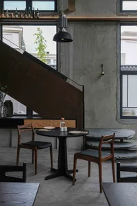 現代餐廳內部，黑桌、椅子、樓梯與盆栽