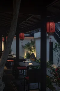 A covered patio dining area with black tables and chairs, wine glasses, and a relaxed atmosphere