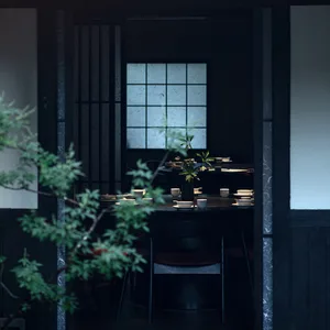 A black and white themed Asian restaurant interior with a dining table, chairs, and a potted plant, creating a cozy and inviting atmosphere