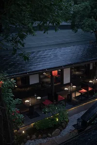 Elegant Asian restaurant with a black roof, wooden floors, and dining tables and chairs arranged throughout the space, with wine glasses on some tables
