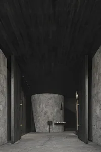 Dark empty room with a stone wall and a wooden door, lit by two lights on either side