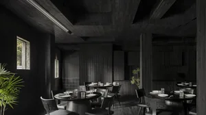 A dark and moody restaurant with a black and white theme, featuring a dining area with tables and chairs, and cups on some tables