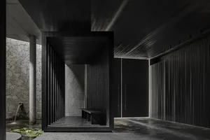 A dark public space with a wooden doorway and a metal-framed bench, possibly a waiting area within a building