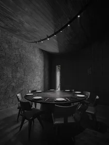Dimly lit dining area with a round table and chairs, creating a mysterious ambiance