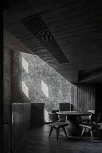 A dark and moody dining area with multiple tables and chairs, creating a cozy atmosphere for patrons
