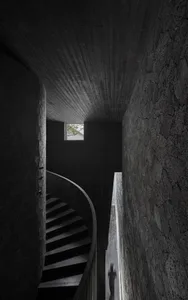 A darkened room with a spiral stone staircase, creating a mysterious atmosphere