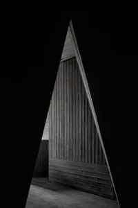 A dark room with a distinctive triangular doorway, possibly leading to another area of a building