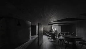 Dark and moody restaurant interior with multiple tables and chairs, wood and stone elements, and minimal natural light