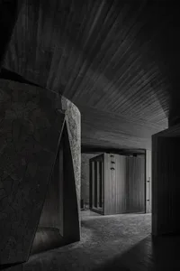A dimly lit hallway with stone walls, featuring two darkened rooms with doors on either side