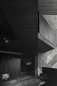 Black and white photo of a building with a concrete staircase leading to a lower level, creating a sense of depth and intrigue