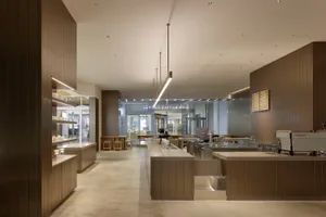 A bustling restaurant kitchen with a large countertop island surrounded by chairs, staff members attending to customers or preparing food