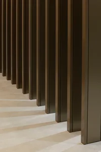 A dimly lit empty hallway with tall wooden pillars on either side, giving an eerie atmosphere