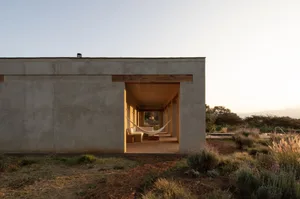 A modern house with a patio area featuring a large window, two chairs, and an inviting atmosphere