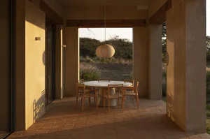 A cozy outdoor dining area with a wooden table and modern chairs, surrounded by a relaxed atmosphere