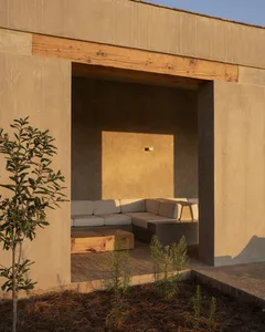 A well-lit outdoor living space with a patio featuring two couches and three chairs around a small table, surrounded by natural scenery