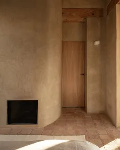 Cozy modern living space with a fireplace, concrete walls, and a doorway to a hallway