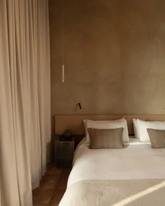 Twin bedroom with two beds, wooden floor, pillows, blankets, and lamps, creating a warm and inviting atmosphere