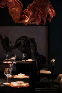 帶有黑色餐桌、椅子、酒杯、碗盤與杯子的精緻餐廳區域，已佈置就餐