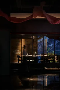Sophisticated dining area with a large wooden table, chairs, and wine glasses, set in a restaurant