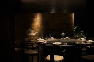 Elegant dining space with a wooden table and chairs, wine glasses, bowls, and cups, surrounded by a sophisticated atmosphere