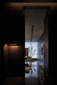 Dimly lit dining room with a wooden dining table and chairs, a potted plant, and a cozy atmosphere